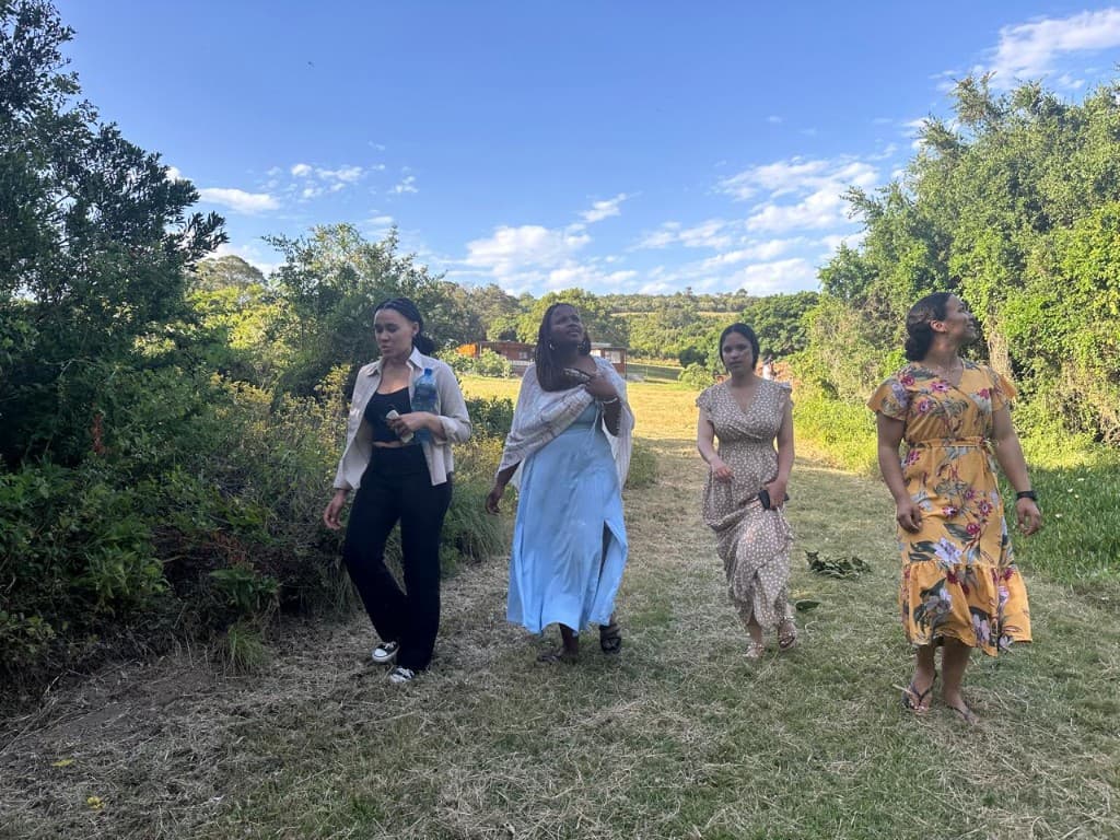 Four women walking together on a grassy path
